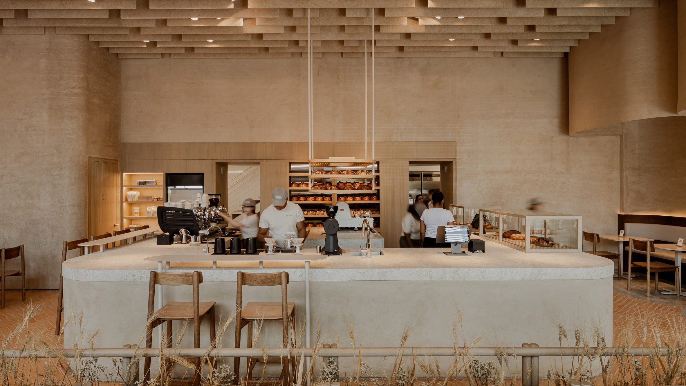 La panadería se articula alrededor de un mostrador en forma de U construido con tierra compactada, una técnica ancestral reinterpretada con elegancia contemporánea.