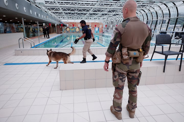 A police officer and a sniffer dog inspect a swimming pool area ahead of the Olympics.