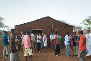 A group of people is gathered outside a small church.