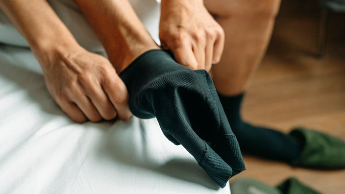 Close-up of man putting on compression socks.