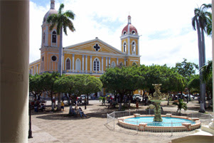 A large church is surrounded by trees. A fountain with a pond is in the foreground.