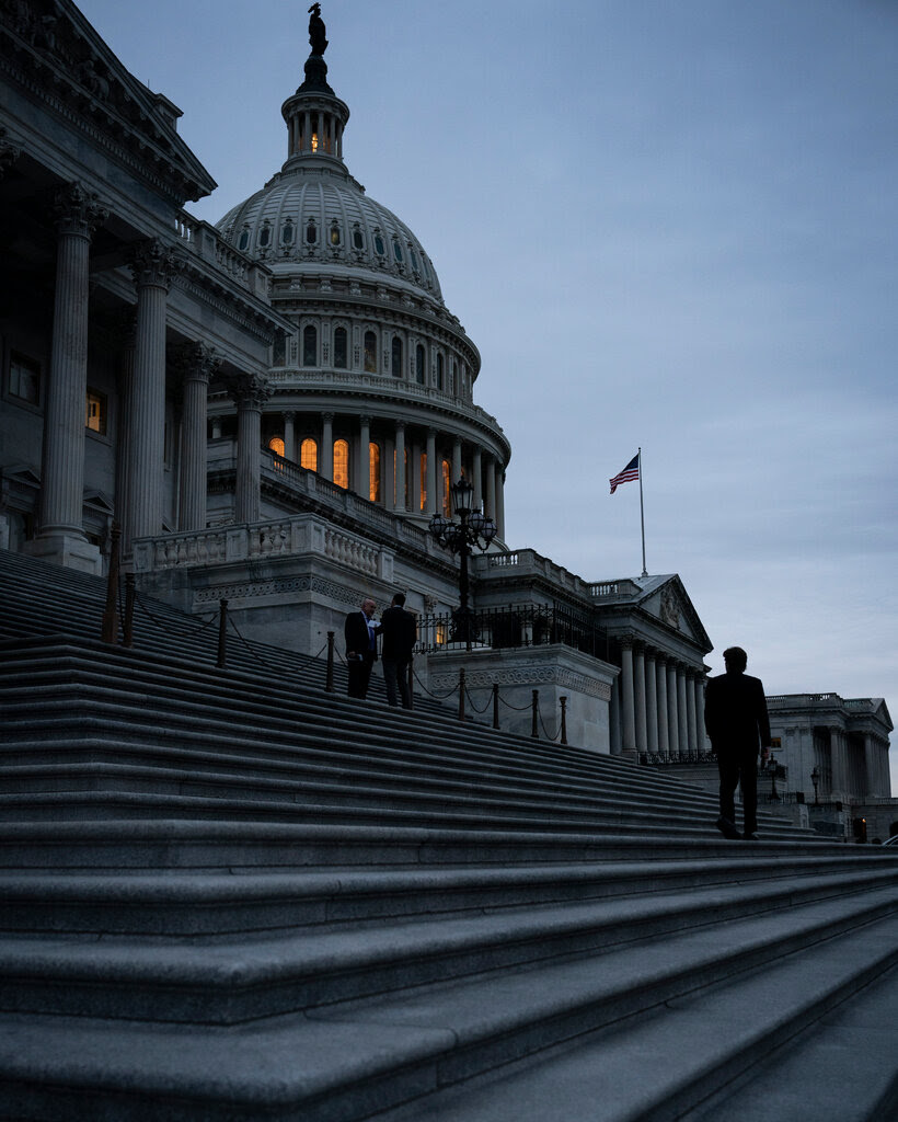 The Capitol illuminated from within in half light.