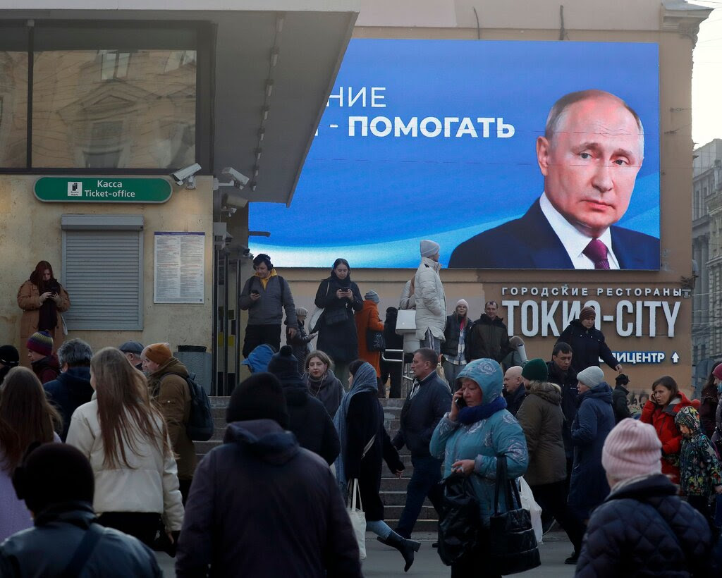 A crowded street with a billboard of Russian president Vladimir Putin’s face.