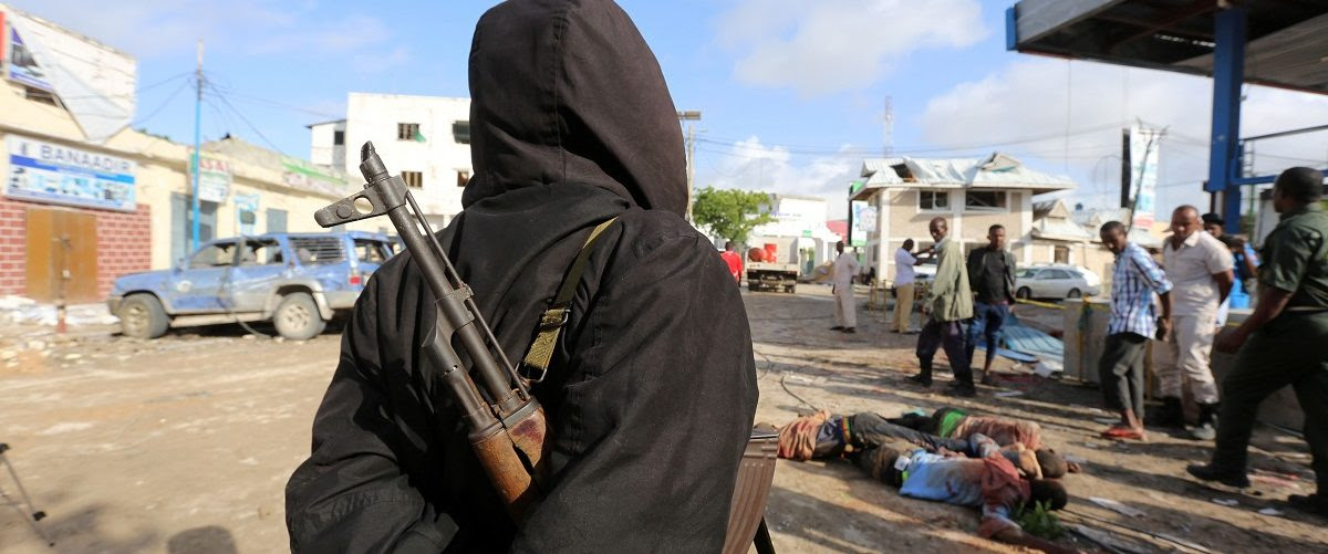 A Somali government soldier views the dead bodies of suspected al-Shabaab militant fighters killed in a suicide bomb attack outside Nasahablood hotel in Somalia's capital Mogadishu