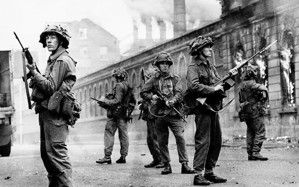 British troops stand guard during rioting in the Falls Road, Belfast, in August 1969