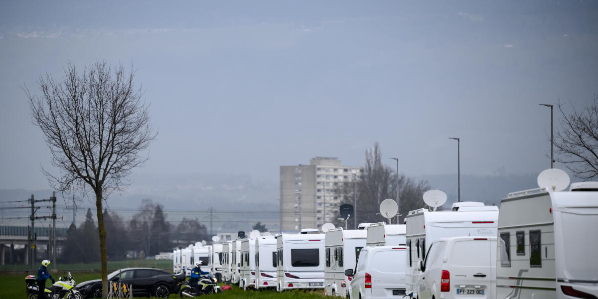 Une vue sur les caravannes des gens du voyage pres du site de Y-Parc avec des policiers de la Police Nord Vaudois le vendredi 8 mars 2024 a Yverdon. Les negociations ont finalement abouti entre le canton de Vaud et les gens du voyage qui s'etaient installes jeudi soir au Chalet-a-Gobet, sur les hauts de Lausanne. Les 43 caravanes presentes sur place ont accepte de partir pour Yverdon. (KEYSTONE/Jean-Christophe Bott)