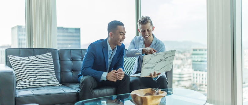 two men in suit sitting on sofa