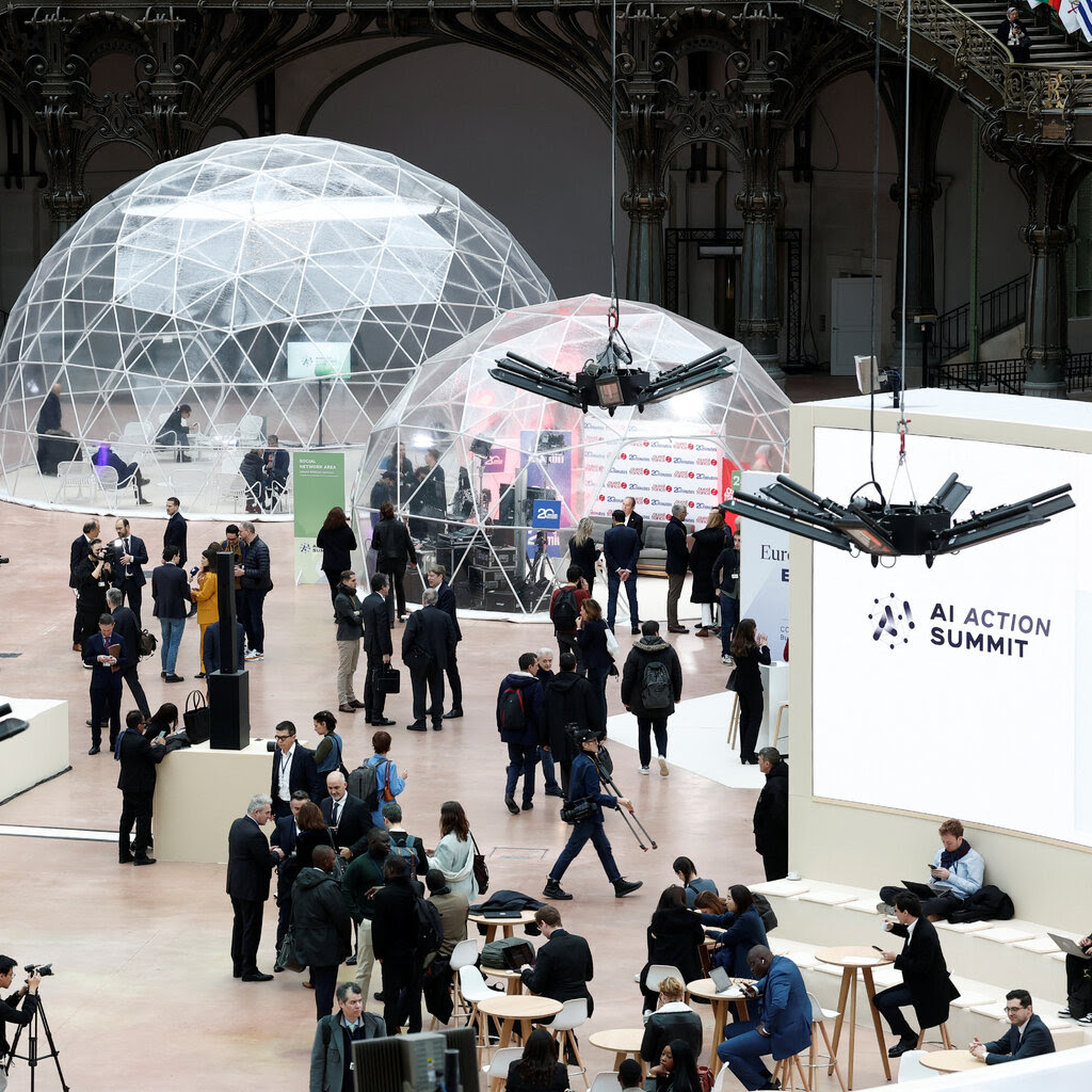 People gathering in a large conference space with clear dome structures set up.