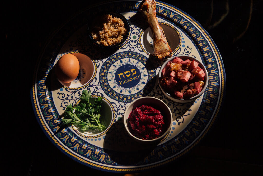 A traditional Seder plate with an egg, two kinds of horseradish, parsley, charoset, and a lamb shank bone.