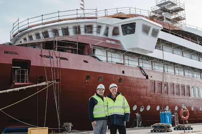 Men standing in front of a large boatDescription automatically generated