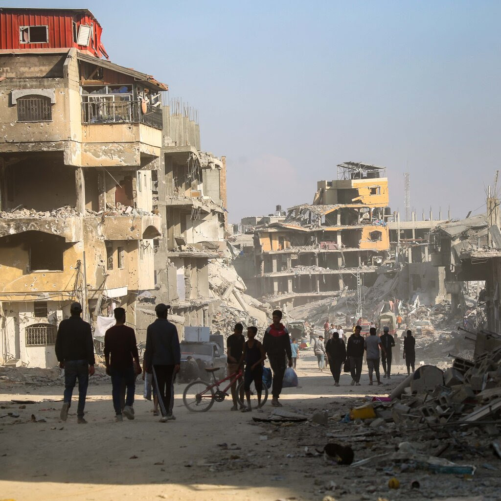 A group of people wander among devastated buildings in Khan Younis, Gaza.