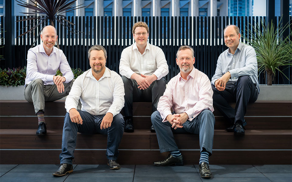 Five managers of Beyond Technology sit together on steps, smiling and posing for a photo.  Their smiles convey warmth and enthusiasm as they capture a moment of shared accomplishment.