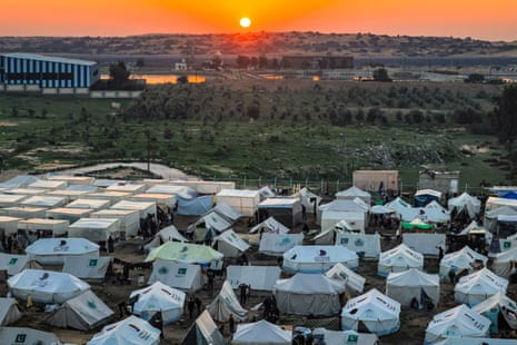 The sun sets in Egypt across the border from the southern Gaza Strip. Tents housing Palestinians displaced by the conflict can be seen in Rafah in the southern Gaza Strip