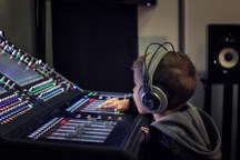 a young boy is at a sound mixing desk, wearing headphones