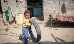 Un niño yemení juega con un neumático de vehículo.