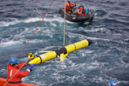 Glider “Adrian” getting deployed from a research vessel while a research team waits on a nearby small boat