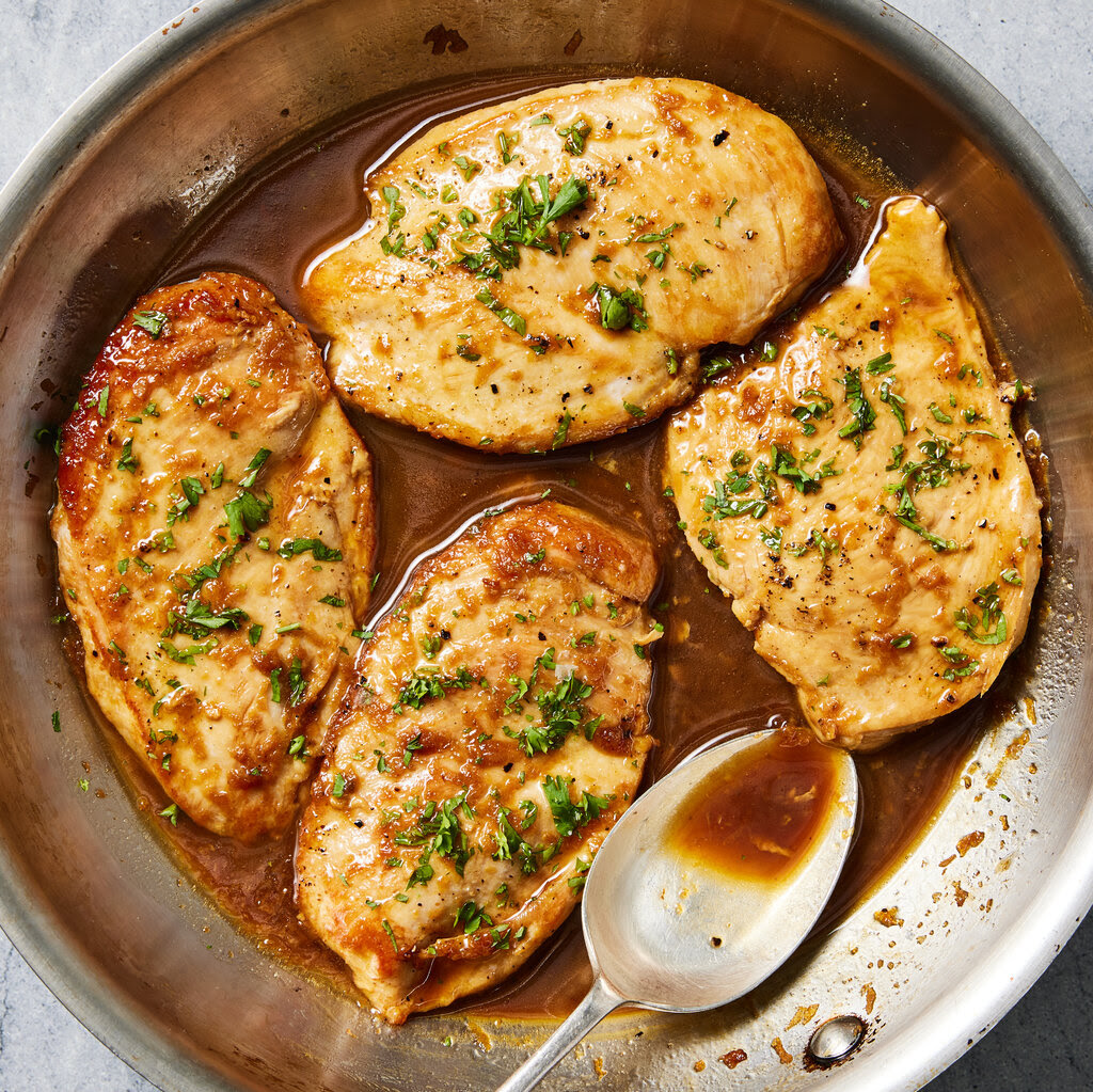 Chicken breasts in a skillet with a brown garlic sauce.