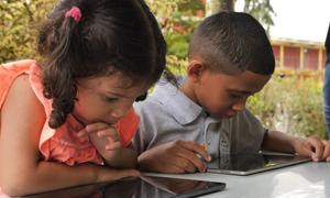 Dos niños venezolanos usan tabletas electrónicas en la escuela.