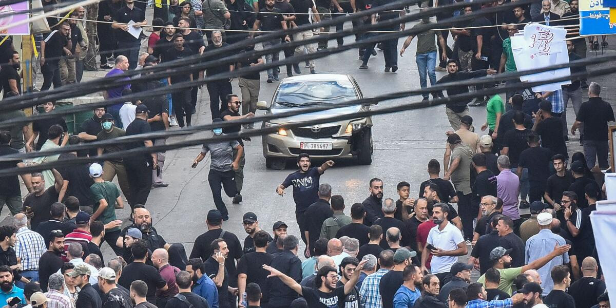 People react around a car after a reported explosion occurred during the funeral of those killed when hundreds of paging devices exploded across Lebanon the previous day, in Beirut’s southern suburbs on September 18, 2024. A second wave of device explosions killed three people in Hezbollah strongholds of Lebanon on September 18, raising fears of an all-out war between Israel and the Iran-backed militants. (Photo by Fadel ITANI / AFP)