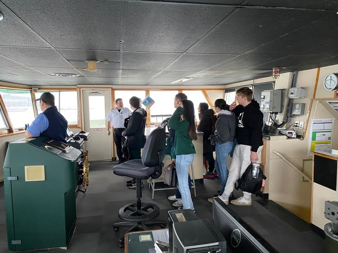 Several people in the wheelhouse of a ferry