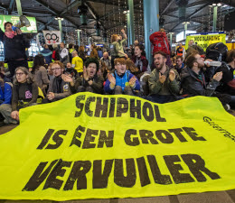 Activisten op Schiphol met een spandoek met de tekst 'Schiphol is een grote vervuiler'