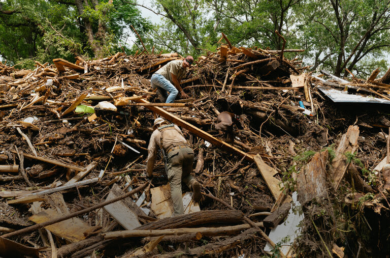 Trabajadores trepan por una maraña de escombros de la inundación.