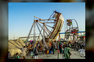 A large group of people is enjoying rides at a carnival.