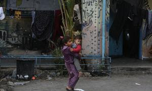 Un niño carga a un bebé en las devastadas calles de Gaza.