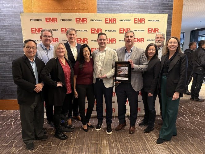 Ten people in front of a backdrop with the Engineering News-Record and Procore logos and one holding a crystal award and one a plaque