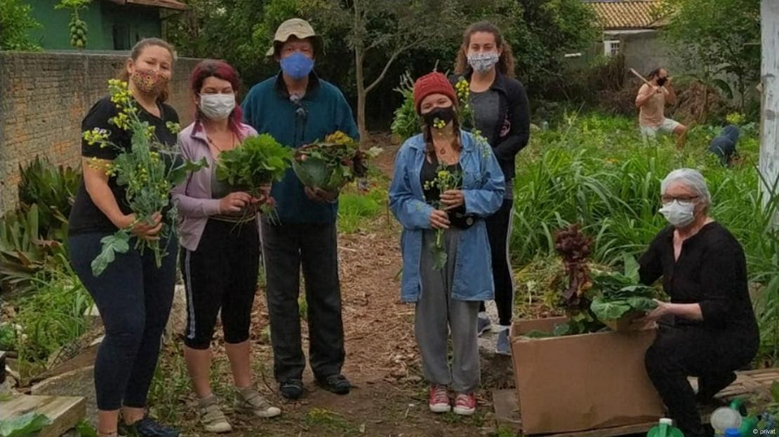 Pessoas de máscara de proteção em meio a horta