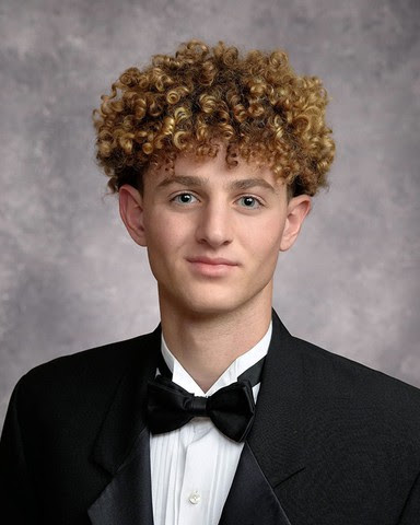 a senior style photo of Beau Couture, he is wearing a black tuxedo jacket, black bowtie and white shirt