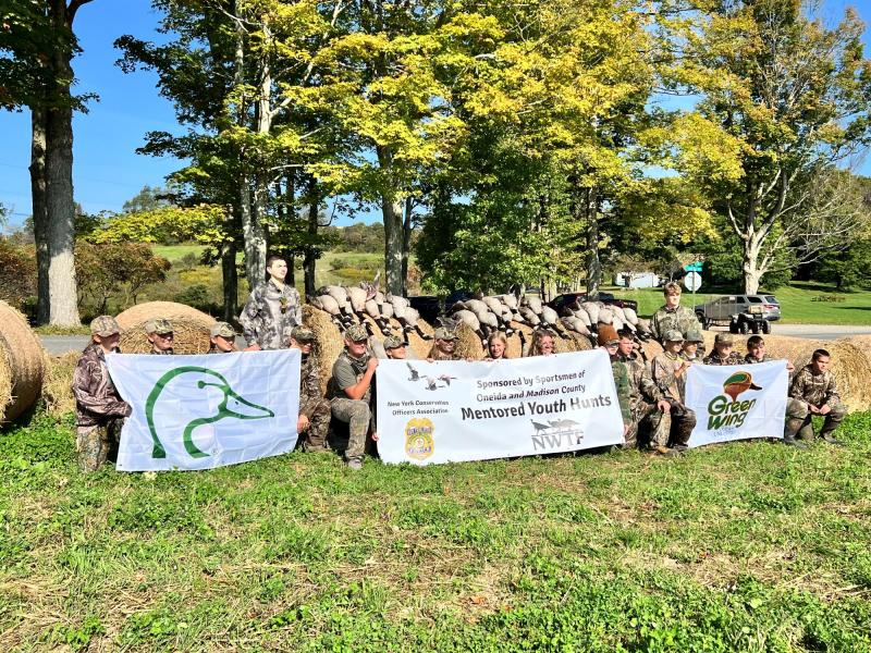 Participants in the youth goose hunt pose for photo with banners