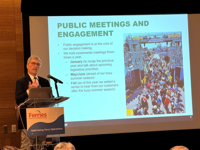 Person behind a podium speaking with a slideshow in the background about public meetings and engagement