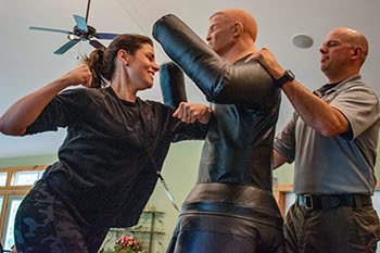 A woman readies her fist to punch a dummy at a BOW self-confidence class.