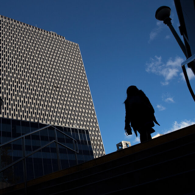 A building in the distance with a shadowed figure walking nearby.