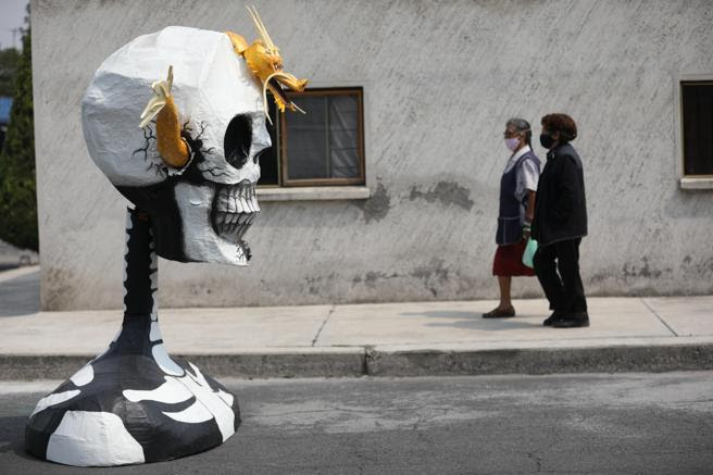 Dos mujeres pasan al lado de una escultura de calavera, este jueves en Tláhuac, en el sureste de la Ciudad de México, México
