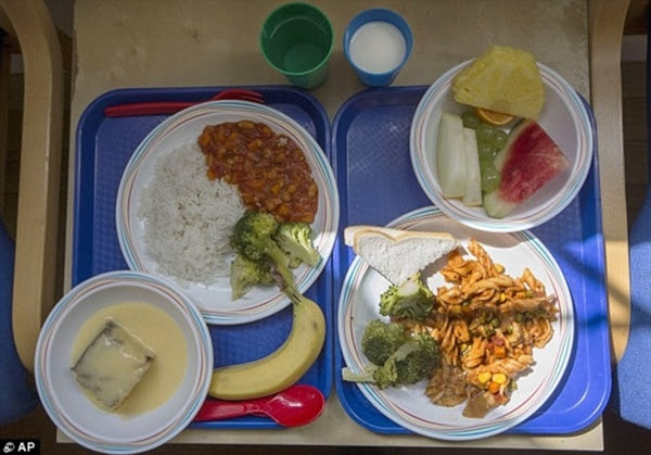 Hai phần ăn tại một trường tiểu học ở London, Anh. Bên phải bao gồm mì ống với bông cải xanh cùng một lát bánh mì và trái cây. Ở bên trái là cơm, rau và súp lơ xanh, bánh bông lan với mãng cầu và chuối để tráng miệng.