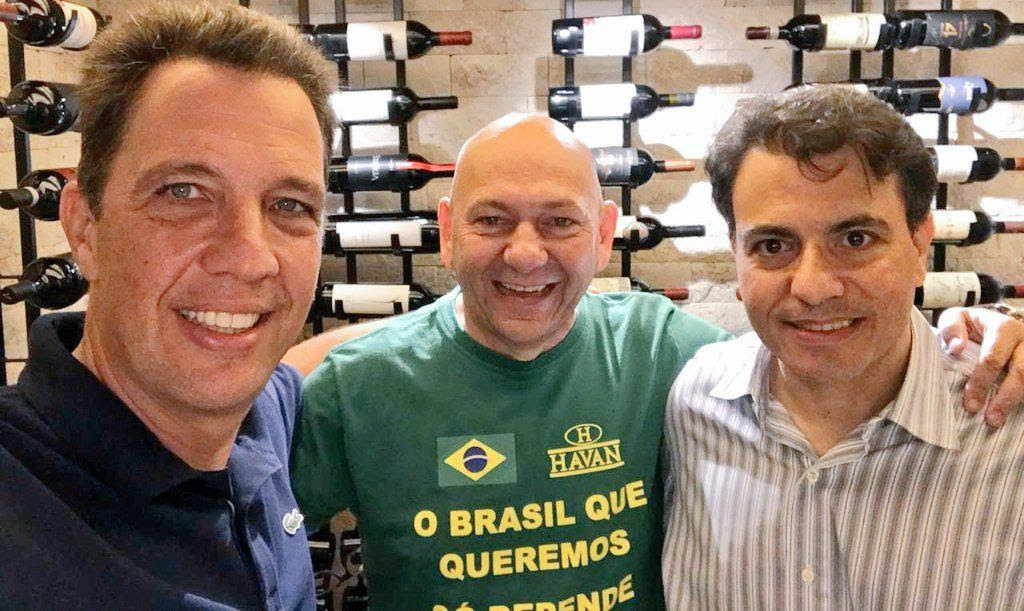 Marcos Bellizia, Luciano Hang e Otávio Fakhoury em visita à sede das lojas Havan na cidade de Brusque, em Santa Catarina; ambos são homens brancos na faixa dos 50 anos