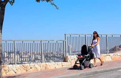 Mother strolls with
                      infant in pram