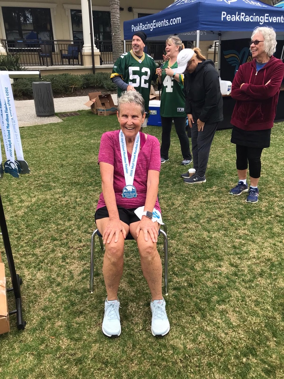 A woman in a pink shirt is sat in a chair on a lawn