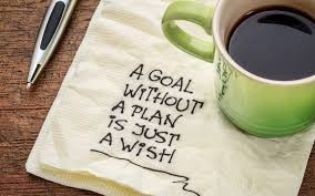  A napkin with the words "A goal without a plan is just a wish", Sitting on the napkin is a cup of coffee and next to it is a pen