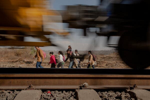 A photograph of a group of people walking parallel to a moving train.