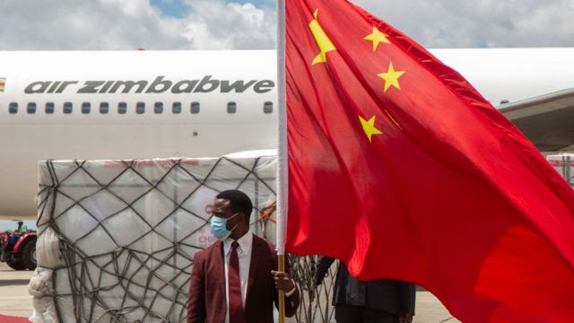 Un homme tient un drapeau chinois avant l'envoi de vaccins Sinovac et Sinopharm à l'aéroport international de Harare, Zimbabwe - mars 2021