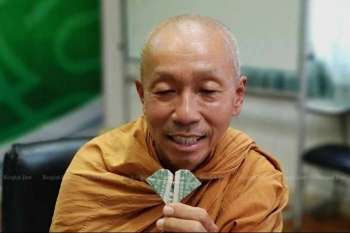 Phra Sutham Nateetong holding an origami heart made from a US$1 bill. From bangkokpost.com