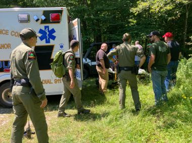rangers standing around with a ambulance open and a person on a stretcher