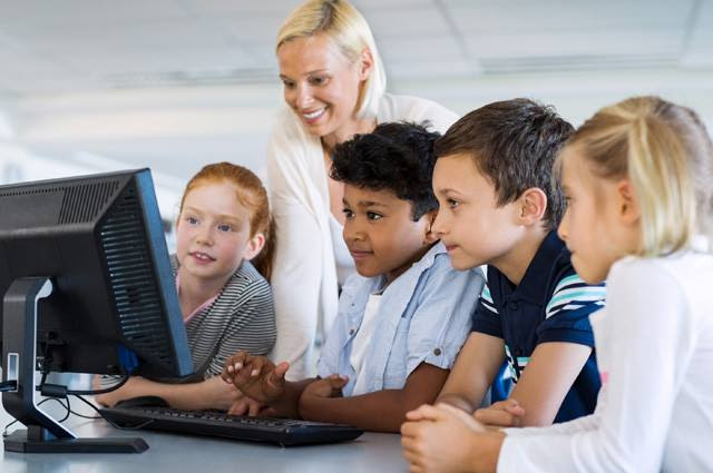 teacher looking at computer with students