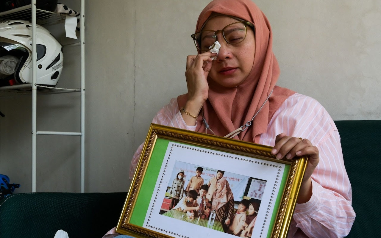 Safitri Puspa Rani cries as she holds a picture of her late son Panghegar Bhumi in Jakarta