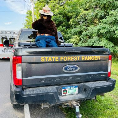 Smokey Bear in the back of a Forest Ranger truck during parade
