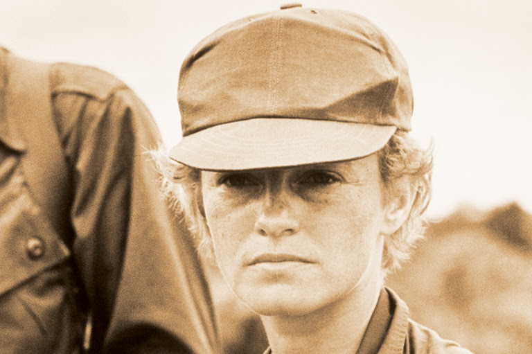 Sepia tone portrait of a woman with a baseball cap on.