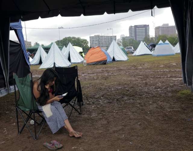 A demonstrator checks her mobile phone inside a tent at a protest area, dubbed the Gota-Go village, where people are gathering in opposition to Sri Lanka's President Gotabaya Rajapaksa near the Presidential Secretariat, amid the country's economic crisis, in Colombo, Sri Lanka, April 12, 2022. REUTERS/Dinuka Liyanawatte